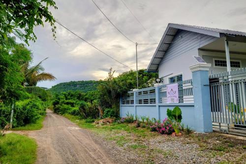 a dirt road next to a blue house at Phnom Sampov Homestay ផ្ទះលំហែភ្នំសំពៅ in Phumĭ Kdaông Khang Tbong