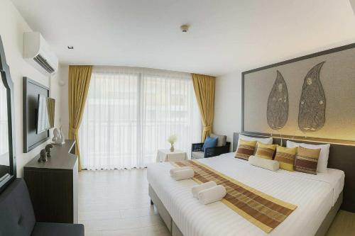 カタビーチにあるStay Kataの大きな白いベッドと黄色い枕のある寝室