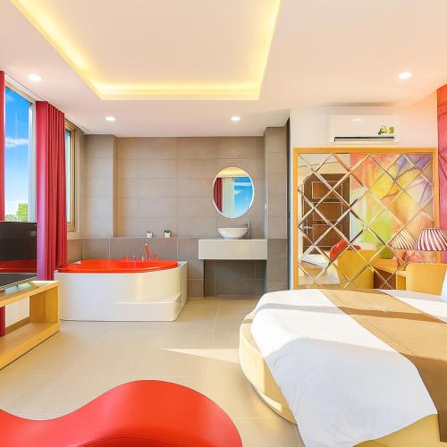 a bedroom with a bed and a tub and a sink at Happy 1 Hotel Binh Duong in Bến Cát