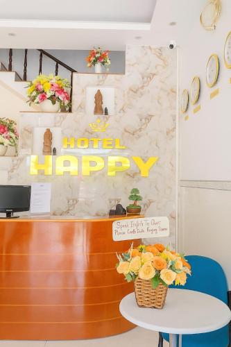 a hotel happy sign on a counter with flowers on a table at Happy 1 Hotel Binh Duong in Bến Cát