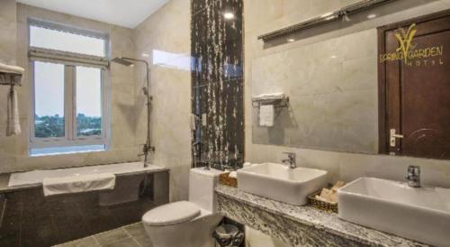 a bathroom with two sinks and a toilet and a window at SPRING GARDEN HOTEL LK in Long Khanh