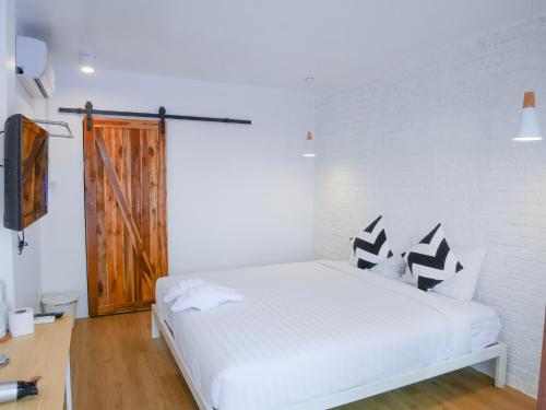a bedroom with a bed with black and white pillows at Baan Rinrak Koh Larn บ้านรินรักษ์ เกาะล้าน in Ko Larn