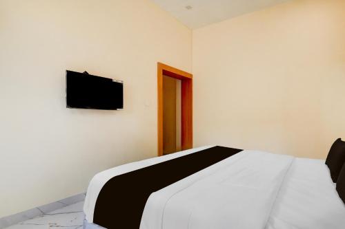 a bedroom with a bed and a flat screen tv on the wall at Super Townhouse Oak Army Aviation Base Jhansi in Jhānsi