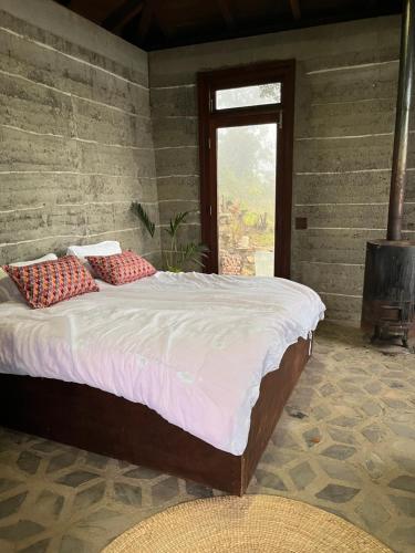 een bed met rode kussens in een kamer met een raam bij Community Lodge Nepal - Chhimeki Lodge in Nagarkot