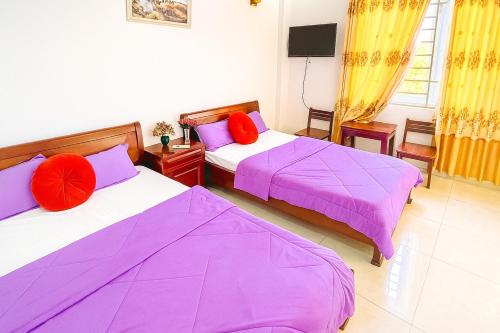 two beds in a room with purple sheets and red pillows at Gia Hoang Hotel in Quy Nhon