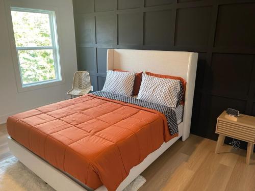 a bedroom with a bed with an orange comforter and a window at Downtown New 3 Story Sleeps 14 in Baton Rouge