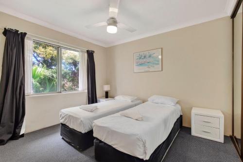 two beds in a room with a window at Coastal Haven Sandcastles 220 in Coffs Harbour