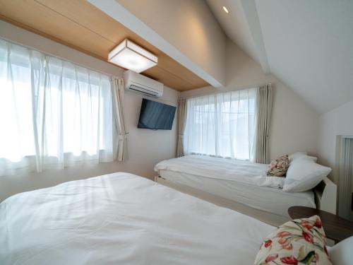 a bedroom with two beds and a window at さくら旅館阿佐谷北千利休 in Tokyo