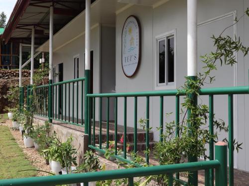 a house with a green fence in front of it at Tez's Backpacking Lodge in Maria