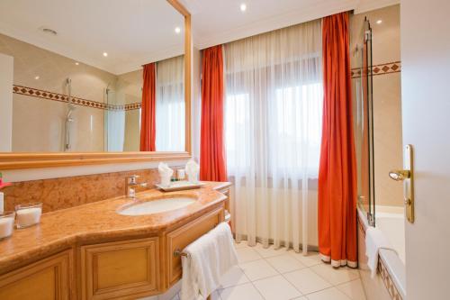 a bathroom with a sink and a large mirror at Central-Hotel Kaiserhof in Hannover