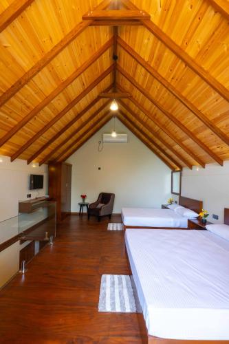 two beds in a room with a wooden ceiling at Sakun villa in Mirissa