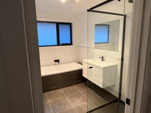 a bathroom with a tub and a sink and a mirror at Green Hill Views - Family Home close to Hobart - 4bed, 2bath in Rokeby
