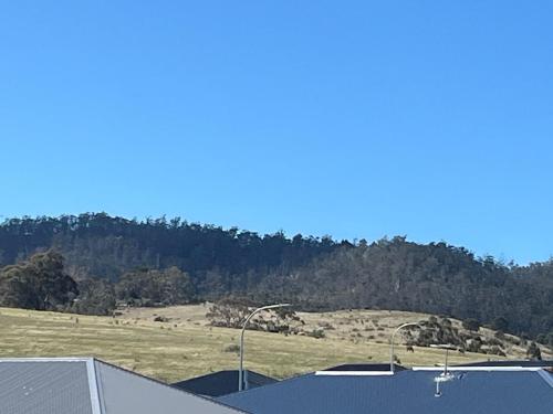 a view of a field and a hill with trees at Green Hill Views - Family Home close to Hobart - 4bed, 2bath in Rokeby