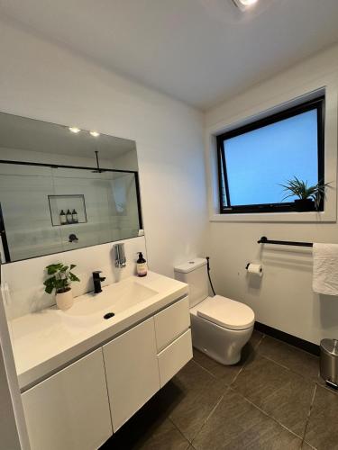 a bathroom with a sink and a toilet and a window at Green Hill Views - Family Home close to Hobart in Rokeby