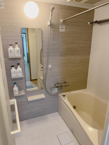 a bathroom with a bath tub and a mirror at The Prime Minato 2-Bedroom Suite Near Tokyo Tower, 2 Mins Walk to Asakusa Line, Direct Access From HND, NRT Airport in Tokyo