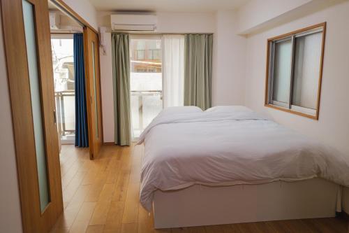 a bedroom with a white bed and a window at 位于新桥的2卧室公寓 in Tokyo