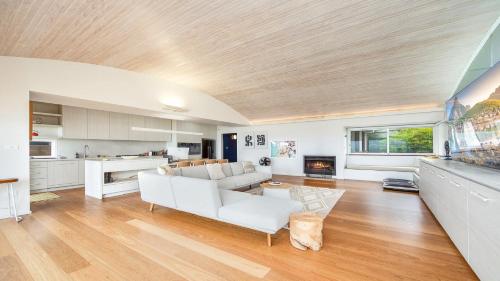 a living room with a white couch and a kitchen at Pearl On The Beach By Holidayco in Umina