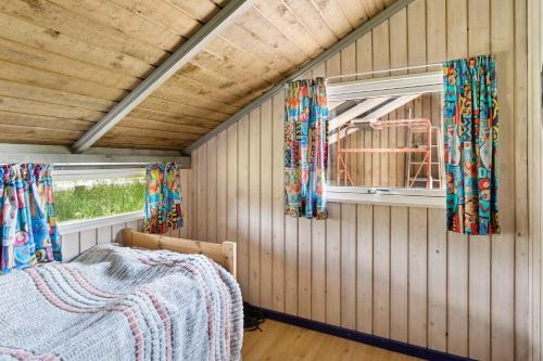 Cette chambre comprend un lit et 2 fenêtres avec des rideaux. dans l'établissement Charming Cottage Near The Water, à Kisserup