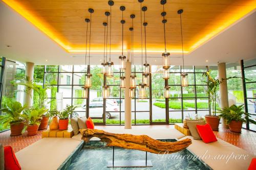 a living room with a large couch and windows at Raincondo Ampere in Cha Am