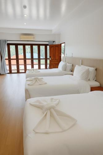 a group of four beds in a room at De Hom Hotel Mae Hong Son in Mae Hong Son
