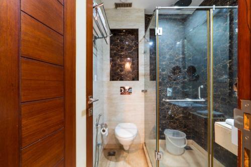 een badkamer met toilet en glazen douche bij Hotel Grand FFOUR in New Delhi