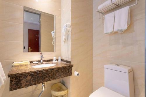ein Badezimmer mit Toilette, Waschbecken und Spiegel in der Unterkunft GreenTree Inn ShanDong Yantai Yantai University Business Hotel in Yantai