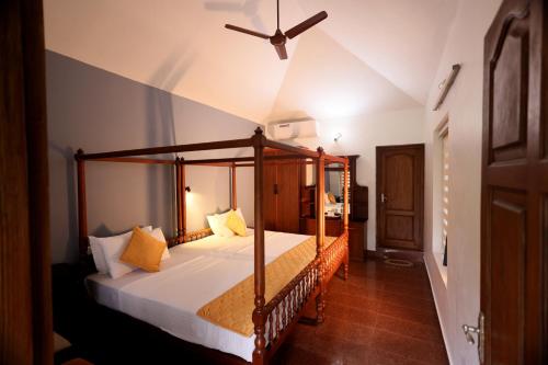Ideal Ayurvedic Resort Kovalam في كوفالام: غرفة نوم مع سرير بمظلة في الغرفة