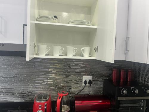 Eine Küche mit weißen Schränken voller weißem Geschirr in der Unterkunft Kys Place in Durban