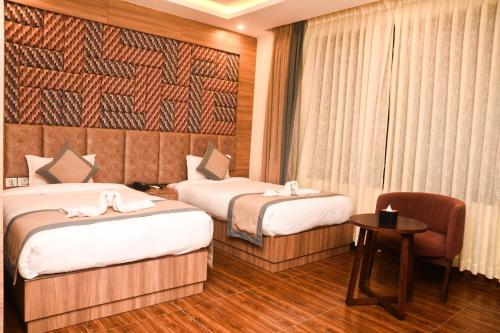 a hotel room with two beds and a chair at Swan Regency in Jogīkuti