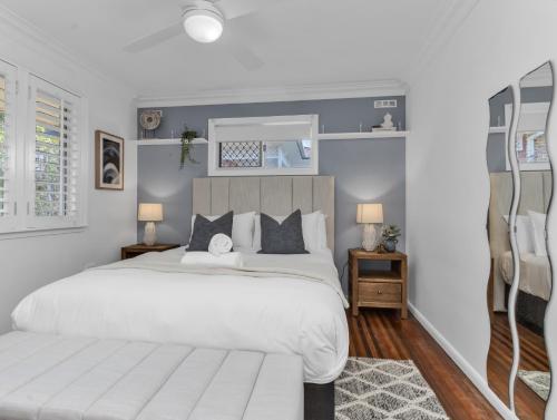 a bedroom with a large white bed and a mirror at Humpback Villa in Kingscliff