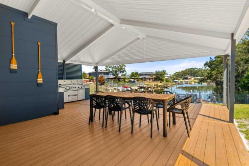 eine Holzterrasse mit Tisch und Stühlen und eine Küche in der Unterkunft The Quay To Sussex in Sussex inlet