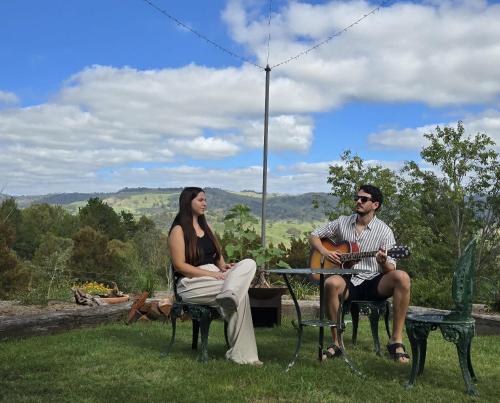 un homme et une femme assis à une table avec une guitare dans l'établissement Kanimbla Sunsets by Tiny Away, à Kanimbla