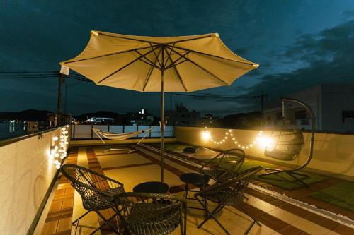 a patio with an umbrella and chairs and lights at みらいステイ牛深 - サウナとバーベキューを楽しむオーシャンビューの一棟貸し別荘 in Amakusa