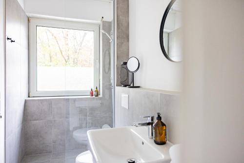 a bathroom with a sink and a toilet and a window at Apartment am Schmölderpark I Klinik I Stadion I Messe I 2 Schlafzimmer I Smart TV I Küche I Balkon in Mönchengladbach