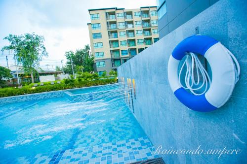 a swimming pool with a lifesaver on the side of a building at Raincondo Ampere in Cha Am