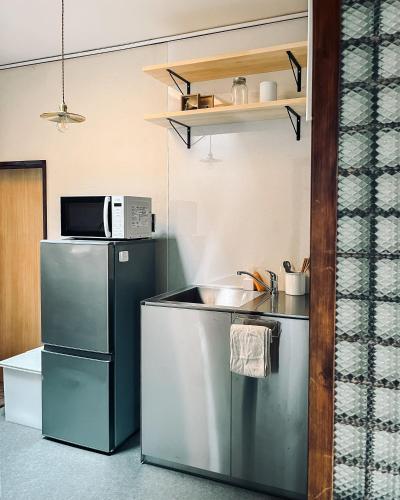 a kitchen with a refrigerator and a sink and a microwave at Hostel Hana An in Tokyo