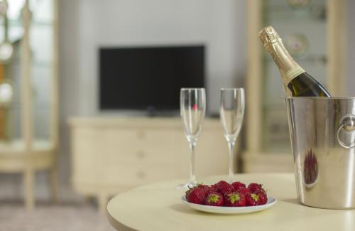 a bottle of champagne and a bowl of strawberries on a table at Bristol Central Park Hotel in Chişinău