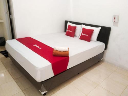 a bed in a room with red and white pillows at RedDoorz near Juwata 3 Airport Tarakan in Karanganyar