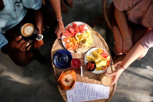 a group of people sitting around a table with bowls of fruit at Nova Surf House in Matara