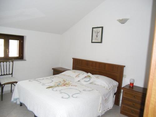 1 dormitorio con 1 cama blanca y 1 silla en Casa Filomena, en Tramonti