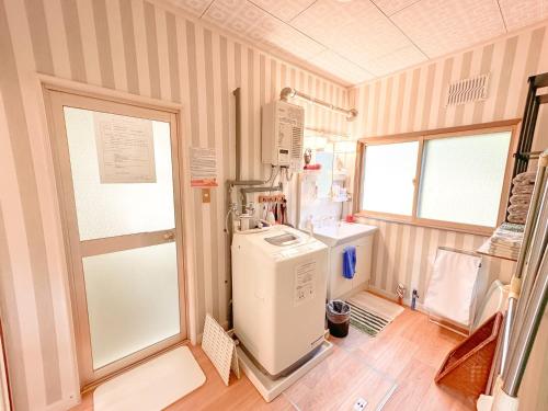 a room with a kitchen with a refrigerator and a window at リニューアル天然温泉マンイの湯 in Shiraoi
