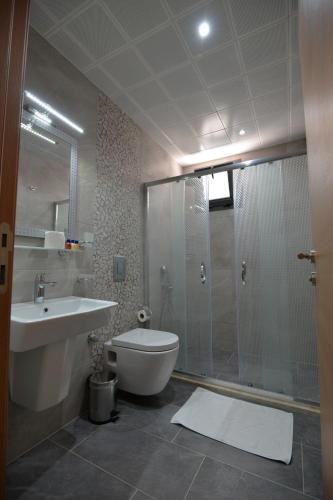 a bathroom with a shower and a toilet and a sink at Arti̇m Apart Hotel in Fethiye