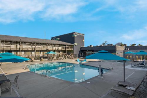 a pool with blue umbrellas and chairs and a building at Richland Riverfront Hotel, an Ascend Collection Hotel in Richland