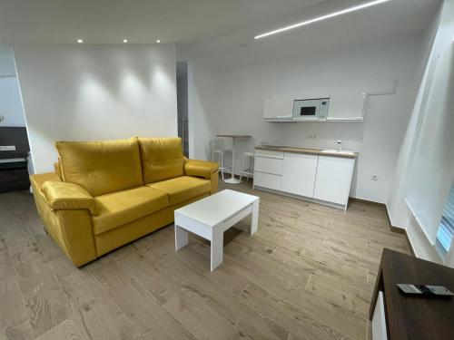 a living room with a yellow couch and a table at Apartamento ALMORCHÓN - Hotel Ruta del Segur in Pontones