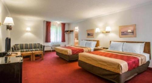 una habitación de hotel con dos camas y un sofá en Baymont by Wyndham Lake George, en Lake George