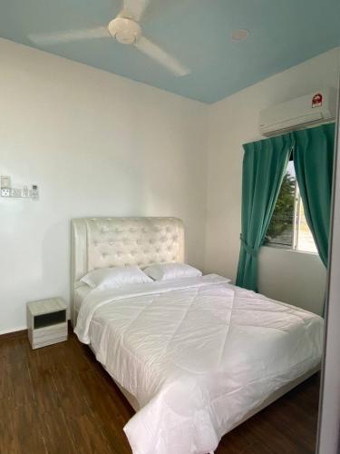 a bedroom with a white bed with a green curtain at Che Deris Garden Cottage with Riverview in Kota Bharu