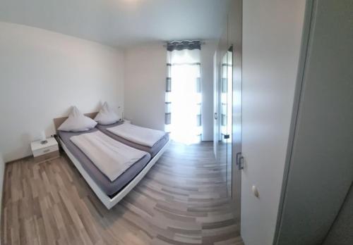 a white bedroom with a bed and a window at Ludwigshöhe EG in Rhodt unter Rietburg
