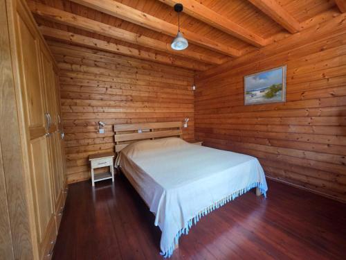 Un dormitorio con una cama en una cabaña de madera. en Chalet Privé avec Piscine 3 Chambres 6 Personnes, en Pointe d'Esny