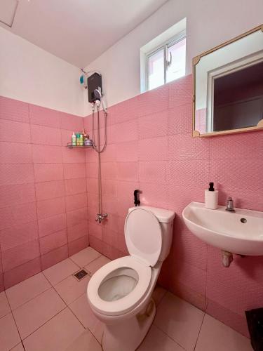 a pink bathroom with a toilet and a sink at Cara Transient house in San Pablo