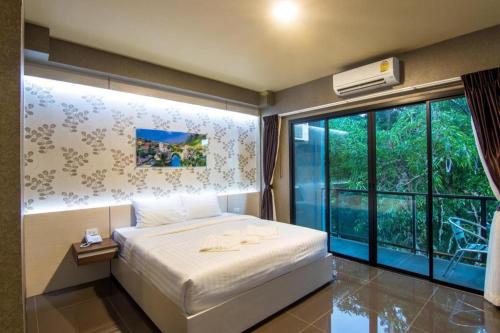 a bedroom with a bed and a large window at Pasub grand hotel in Udon Thani